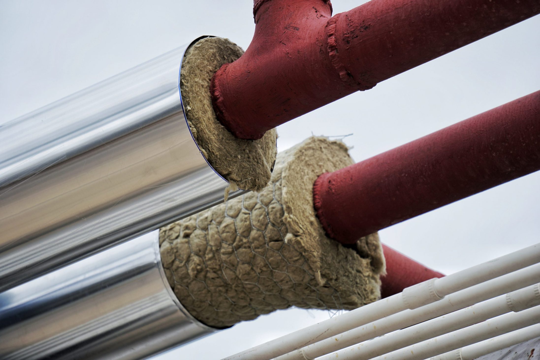 Close-up of insulated hot water pipes with mineral wool and metal cladding